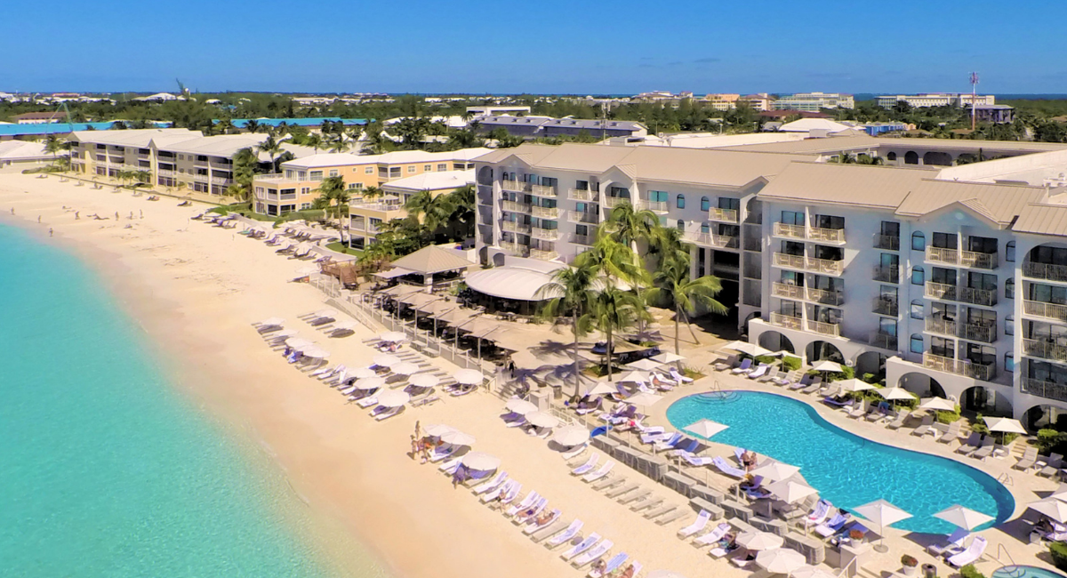 Arial shot of the bright blue ocean, beach, pool and buildings that make up Grand Cayman Marriott Beach Resort