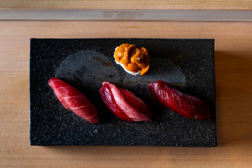 three pieces of tuna sushi on a black plate