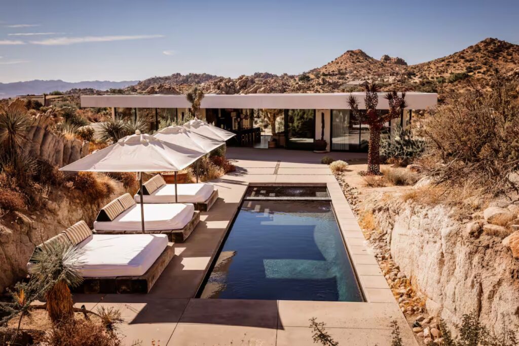 pool and lounge chairs surrounded by desert at joshua tree glass villa