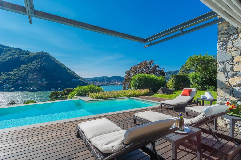 view of a lakeside villa in lake como with lawn chairs greenery and pool