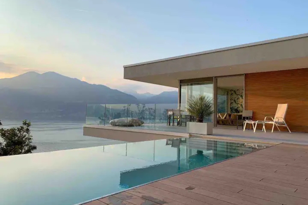 infinity pool looking out onto lake garda with glass walls and wood panneling