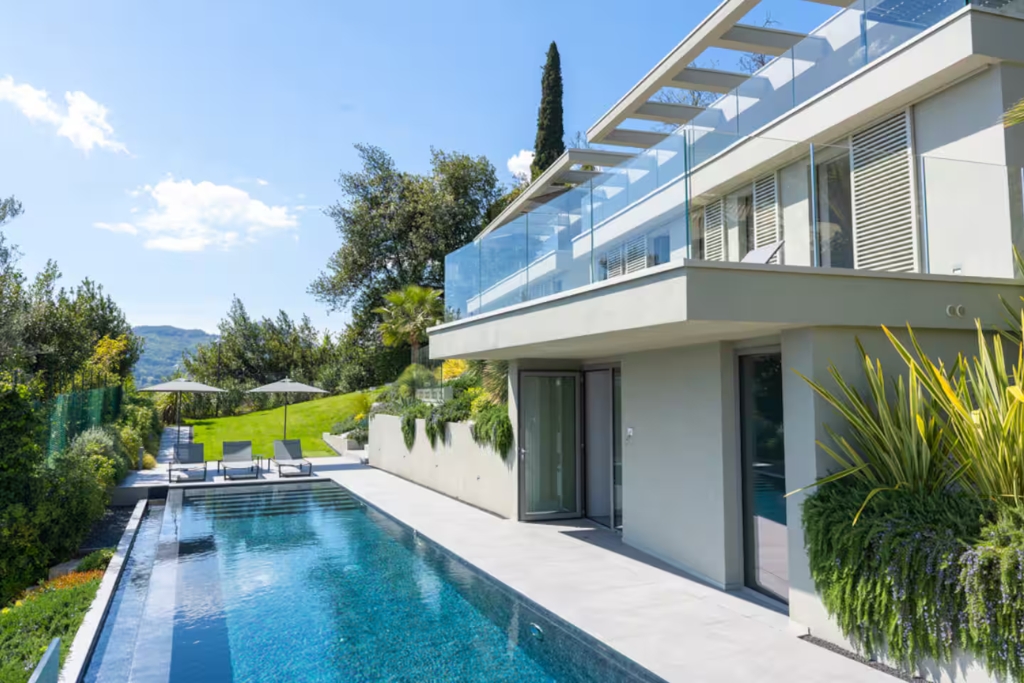 all white modern house in lake garda with pool greenery and lounge chairs