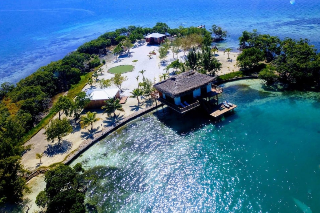 overhead view of a cabin in belize that sits on the blue ocean