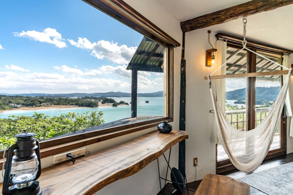 treehouse cabin in japan with a hammock and large open windows looking out on the ocean