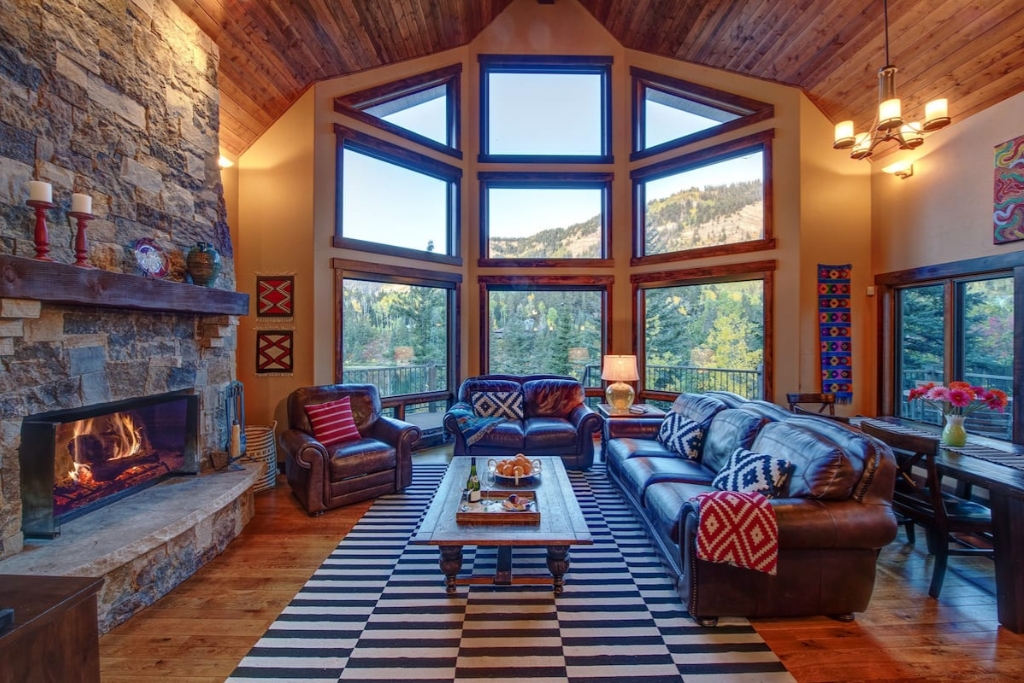 living room of a cabin in colorado with a big brick fireplace and brown couches and open windows