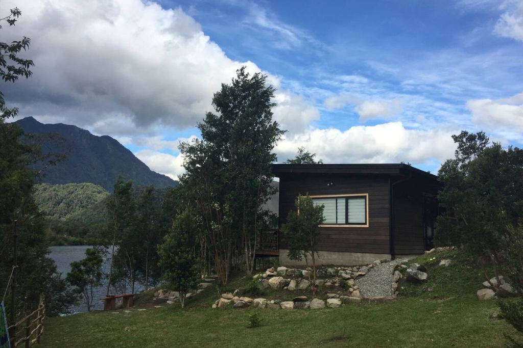 brown cabin with rocks over green grass and a with a mountain view