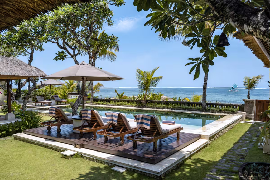 pool in grassy backyard with umbrella loungechairs and ocean view leading to bali beach