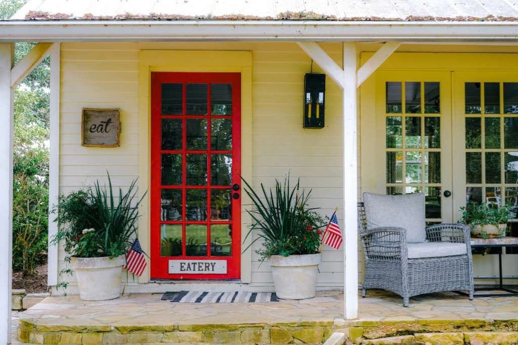 front porch with a bold red door of a rustic eatery in round top texas
