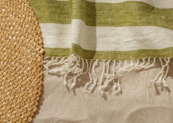 linen beach towel and straw hat in sand