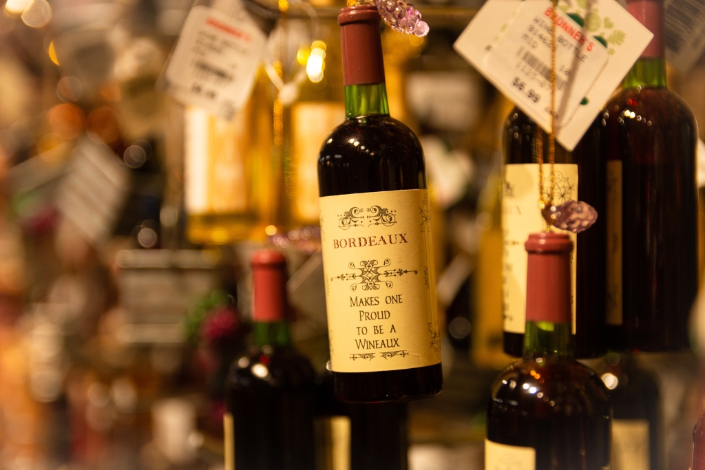 a bottle of bordeaux red wine in a green bottle with a red top hanging with other bottles hanging in the background