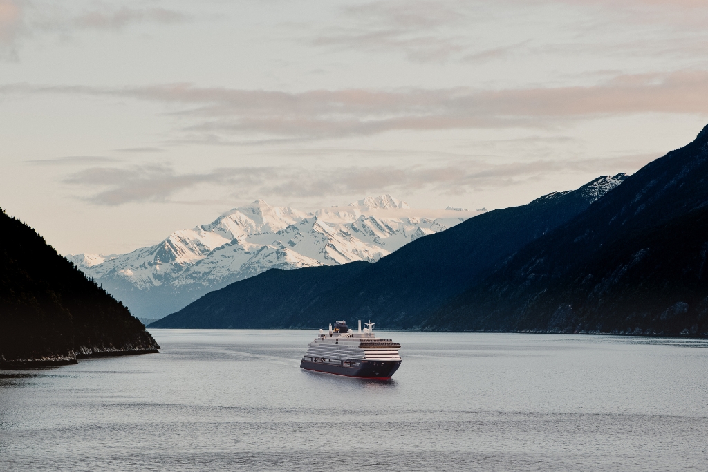 Mountains outlining the ocean with the explora journeys cruise boat down the middle and snowy mountains in the back