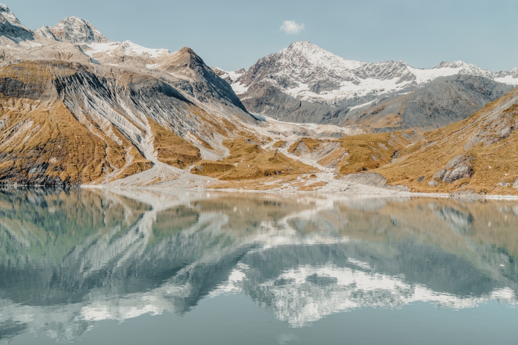 Alaska mountains that are brown at the bottom and snowy at the top and are being reflected through the water