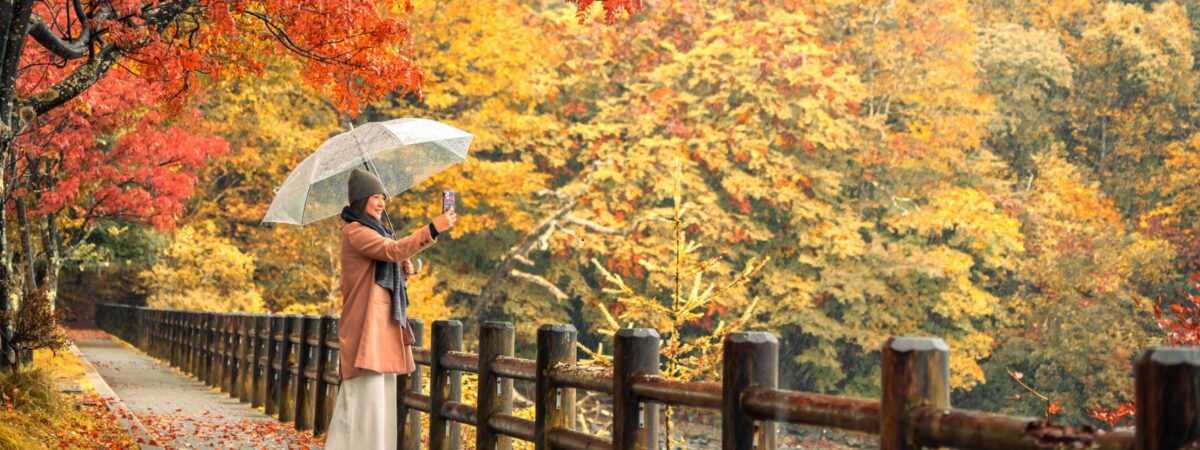 women walking in fall leaves with umbrella