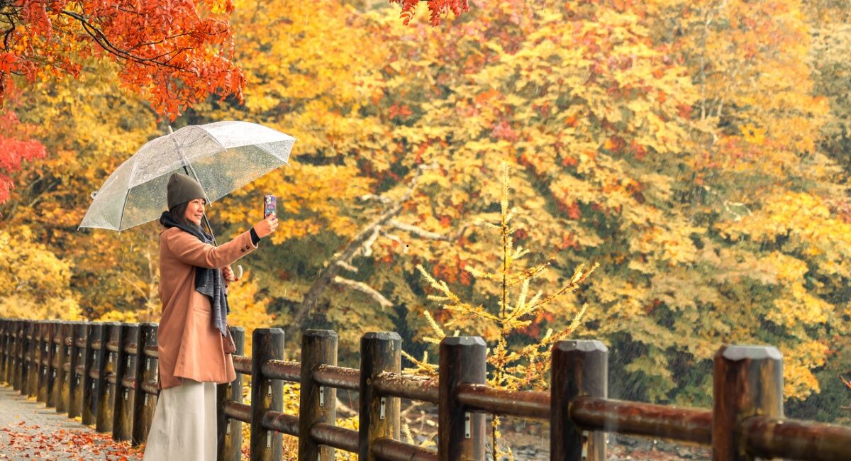 women walking in fall leaves with umbrella
