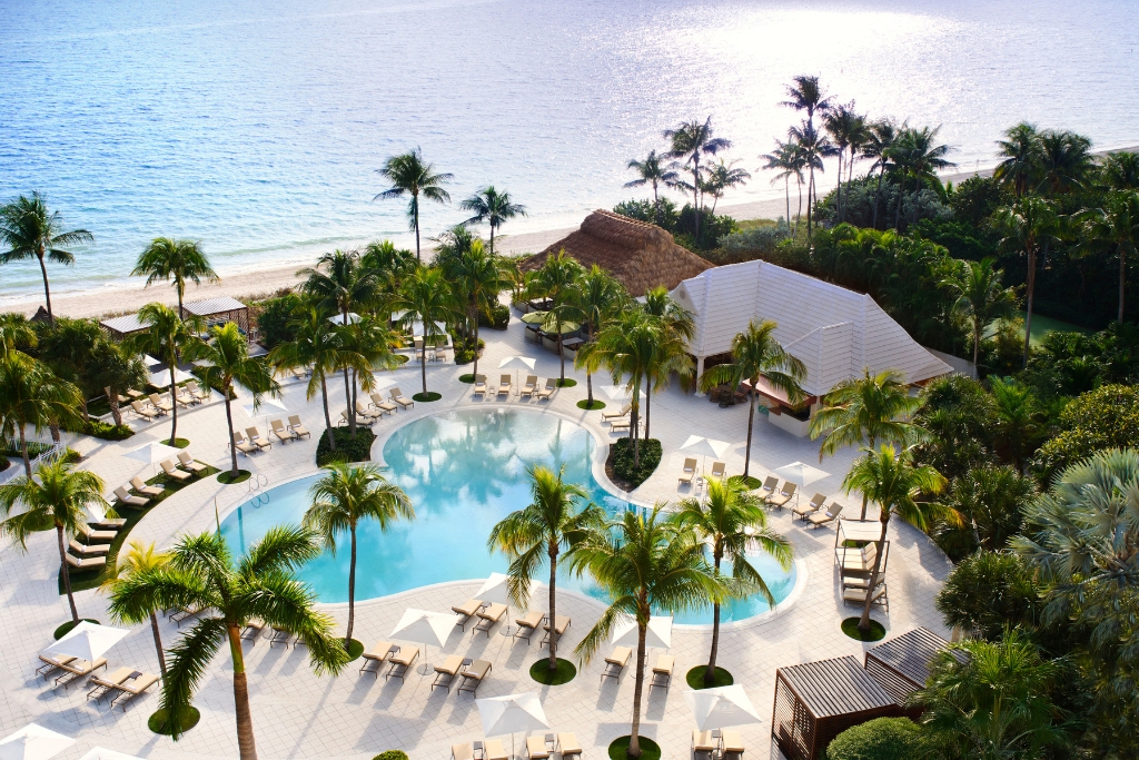 heart shaped pool surrounded by palm trees and cabanas and lounge chairs and a view of the beach in the ritz carlton key biscayne