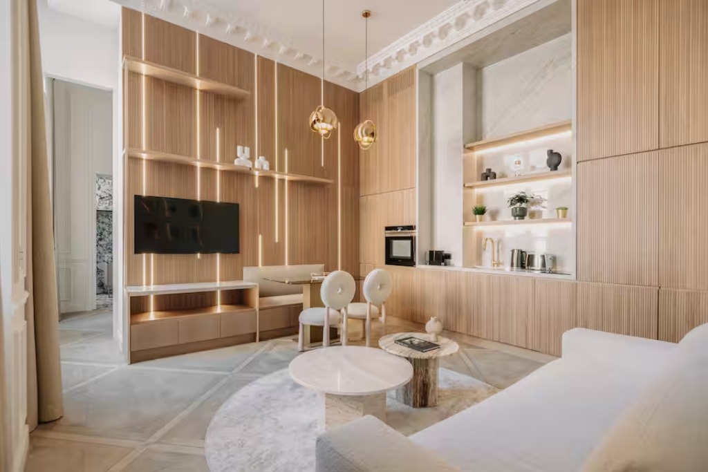 modern apartment in paris with light wooden panelling and crown molding and gold light fixtures hanging from the ceiling
