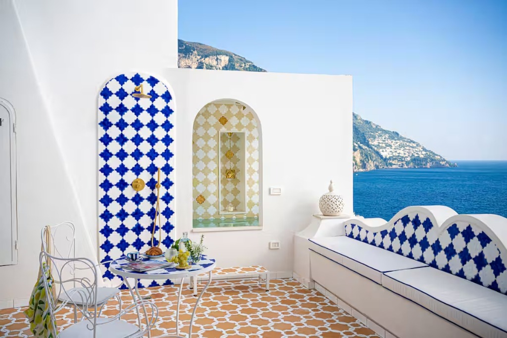 balcony of a home in positano with a tiled floor and outdoor shower and view of the ocean and mountains 