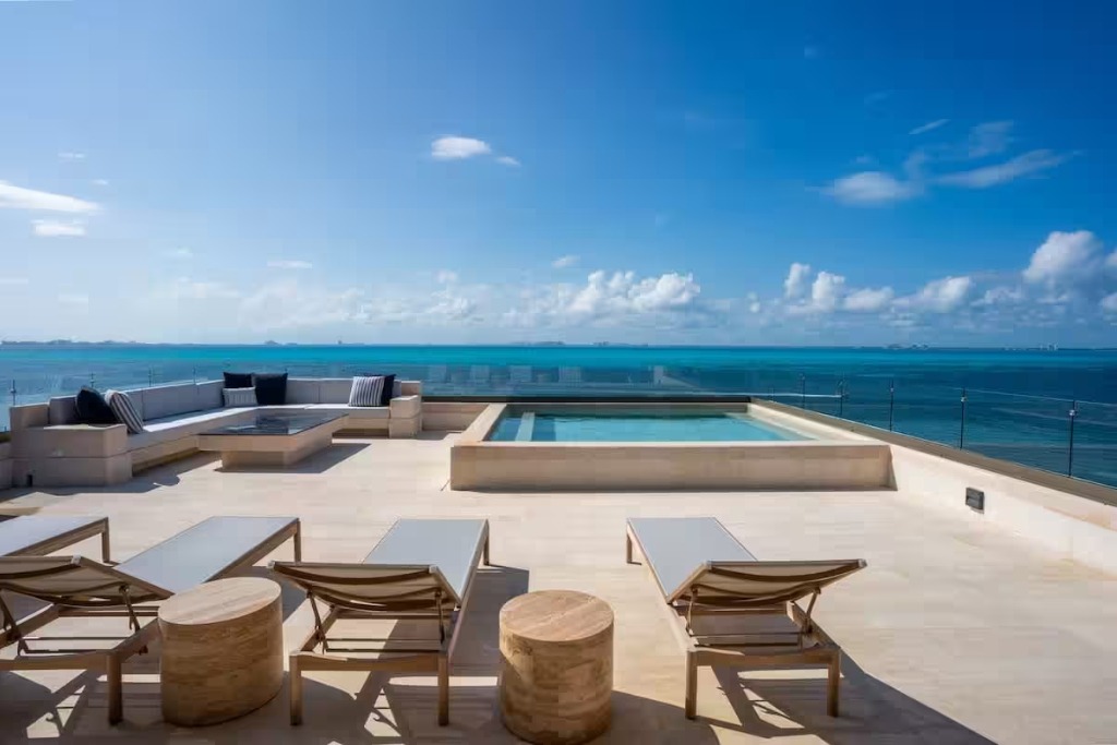 terrace of a honeymoon suite in mexico glass walls and a couch and lounge chairs and a hot tub