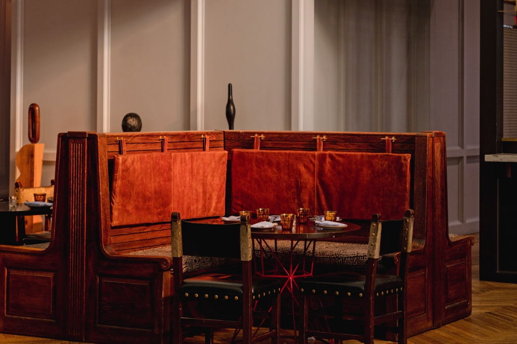 wooden booth with red cushions and green chairs with plates and napkins set up on the circular wooden table