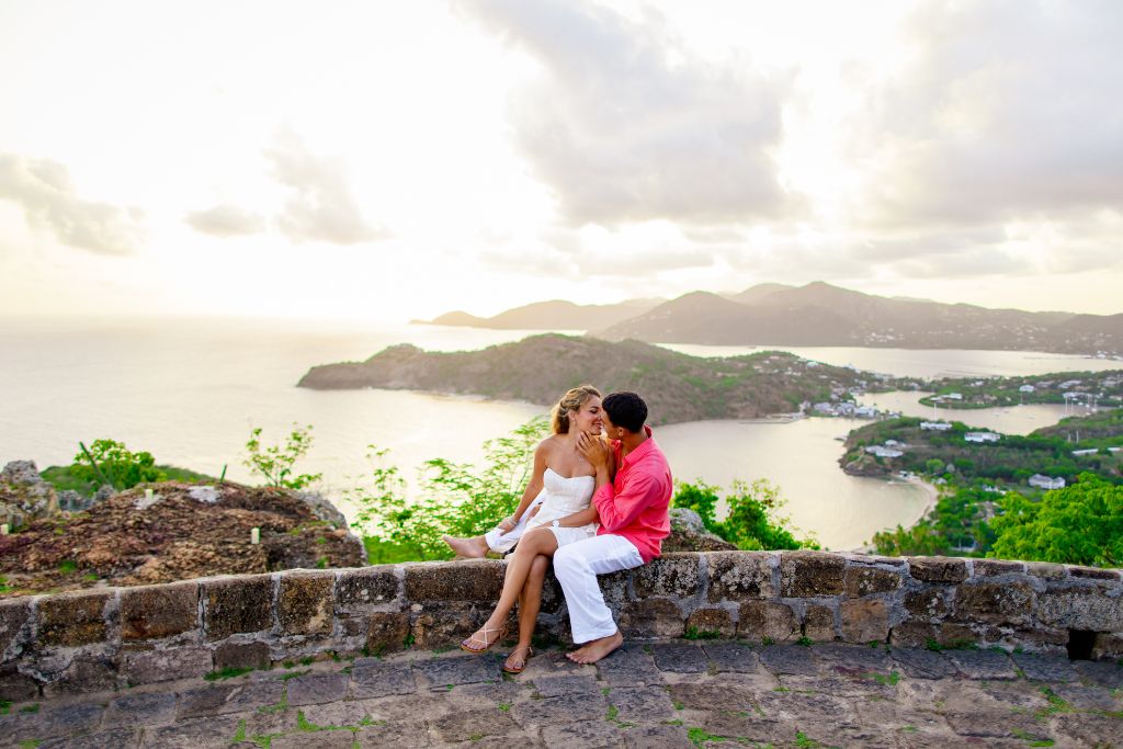 couple on cobblestone wall with views of antigua