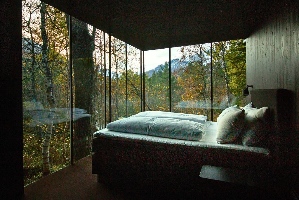 bedroom suite with floor to ceiling glass windows and forest view