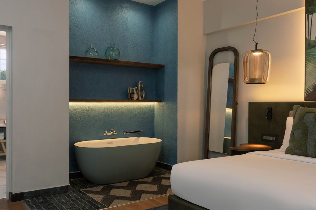 room with blue accent wall, blue bathtub, and green and blue furnishing accents
