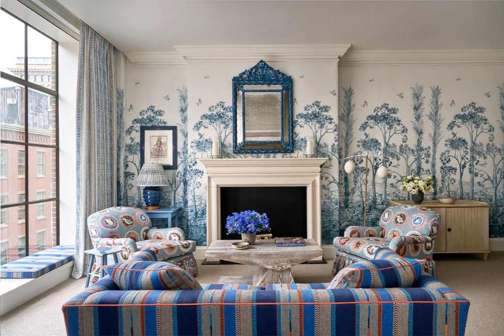 firmdale hotel luxury one bedroom suite living room with a fireplace, blue floral wall paintings, and blue and orange accents