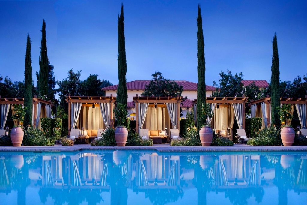 pool with cabanas at dusk with red hotel roofs in background